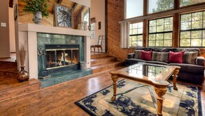 A spacious living room with a fireplace, a large window, and a cozy seating area.
