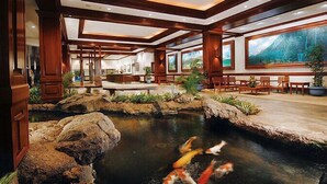 A hotel lobby with a koi pond, wooden furniture, and large windows. - 30% Off Now! Luxury One Bedroom - Free Parking! &  Free WiFi!! (Unknown)