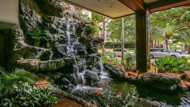 A waterfall feature with a koi pond, surrounded by tropical plants, in a hotel lobby. - 30% Off Now! Luxury One Bedroom - Free Parking! &  Free WiFi!! (Unknown)