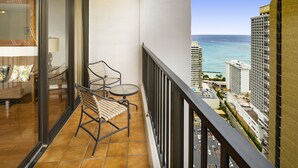 A balcony with a sofa, two chairs, and a small table. It overlooks a cityscape with tall buildings and a view of the ocean. - 30% Off Now! Luxury One Bedroom - Free Parking! &  Free WiFi!! (Unknown)