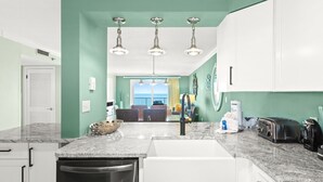 A kitchen with white cabinets, a granite countertop, a dishwasher, a toaster, and a view to the outside. - 🌊 Views That Go On Forever (Destin)