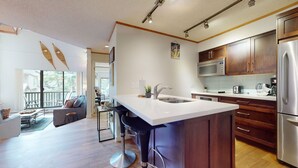 A modern kitchen with a large island, stainless steel appliances, and wooden cabinets.
