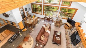 A spacious living area with a large brown sofa, a dining table, and a kitchen area.