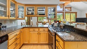 A modern kitchen with wooden cabinets, granite countertops, and a built-in stove.