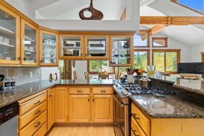 A modern kitchen with wooden cabinets, granite countertops, and a built-in stove.