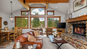A spacious living room with a stone fireplace, large windows, and a cozy seating area.