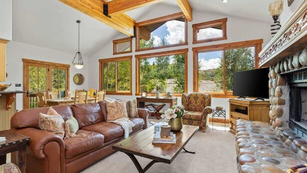 A spacious living room with a leather sofa, a coffee table, and a stone fireplace.