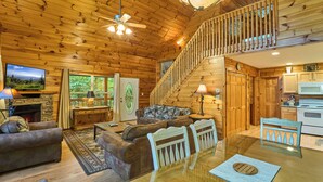 Ein Holzblockhaus im Inneren mit Wohnzimmer, Essbereich, Küche und einer Treppe.