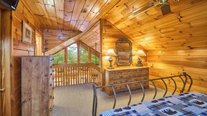 Ein Holzblockhaus-Interieur mit Bett, Kommode und Spiegel.