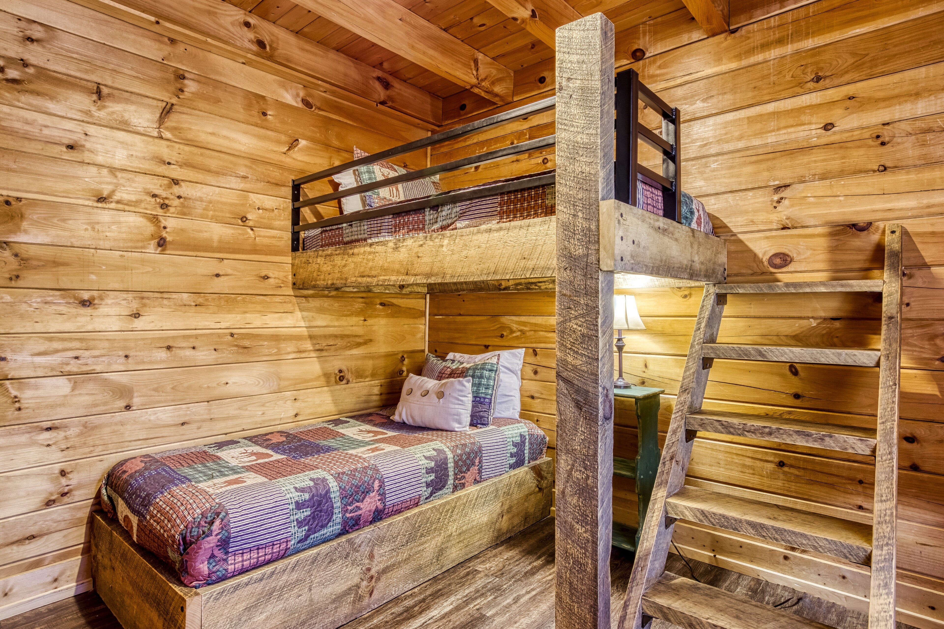 Un lit superposé avec un matelas matelassé, une échelle et un mur en bois.