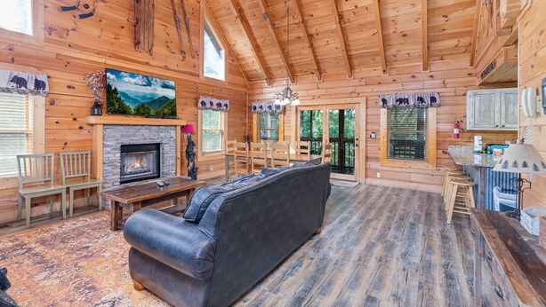 A log cabin interior with a fireplace, wooden furniture, and a large window. - ER101 - Heavenly Hideaway  Great location - Close to town! (Pigeon Forge)