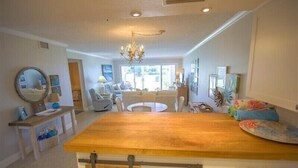 A modern kitchen with a wooden countertop, a chandelier, and a dining area with a round table.