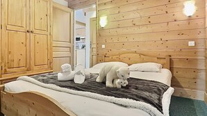 A wooden-paneled room with a bed, a wardrobe, and a mirror.