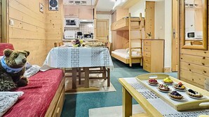 A compact room with a bunk bed, a small table with food, and a teddy bear.
