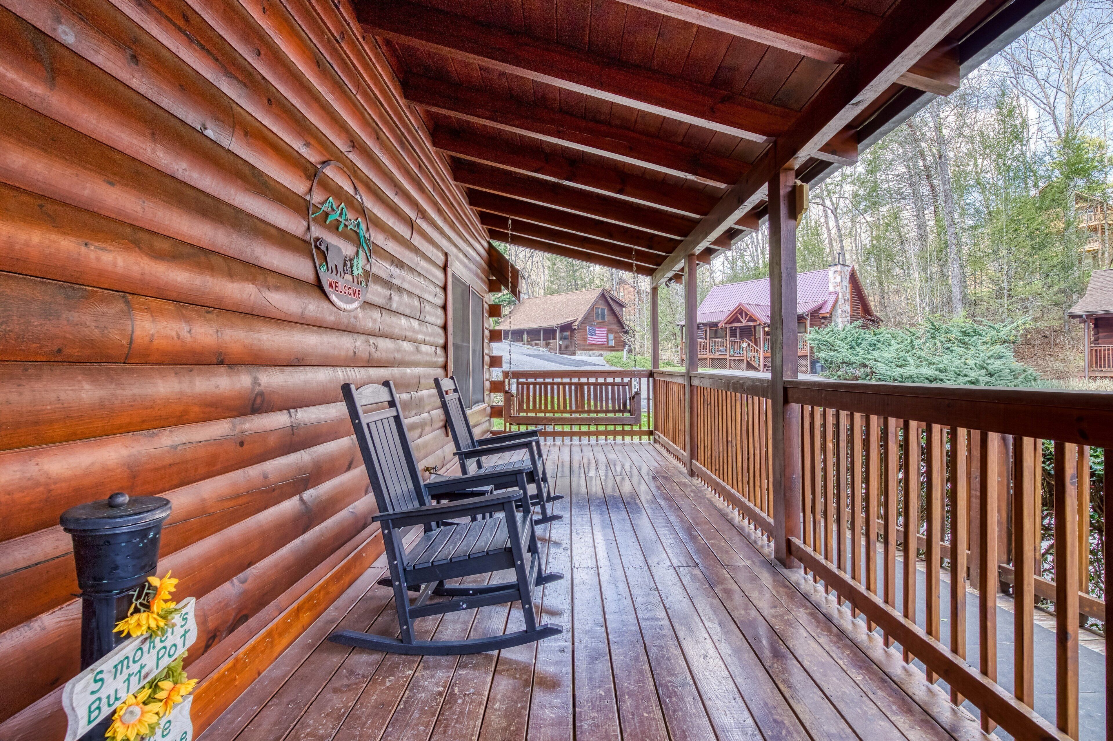 Une cabane en bois dotée d’une véranda, de fauteuils à bascule et d’une pancarte accueillante.