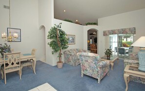 Una sala de estar con comedor, una planta grande en maceta y vistas a través de un ventanal.