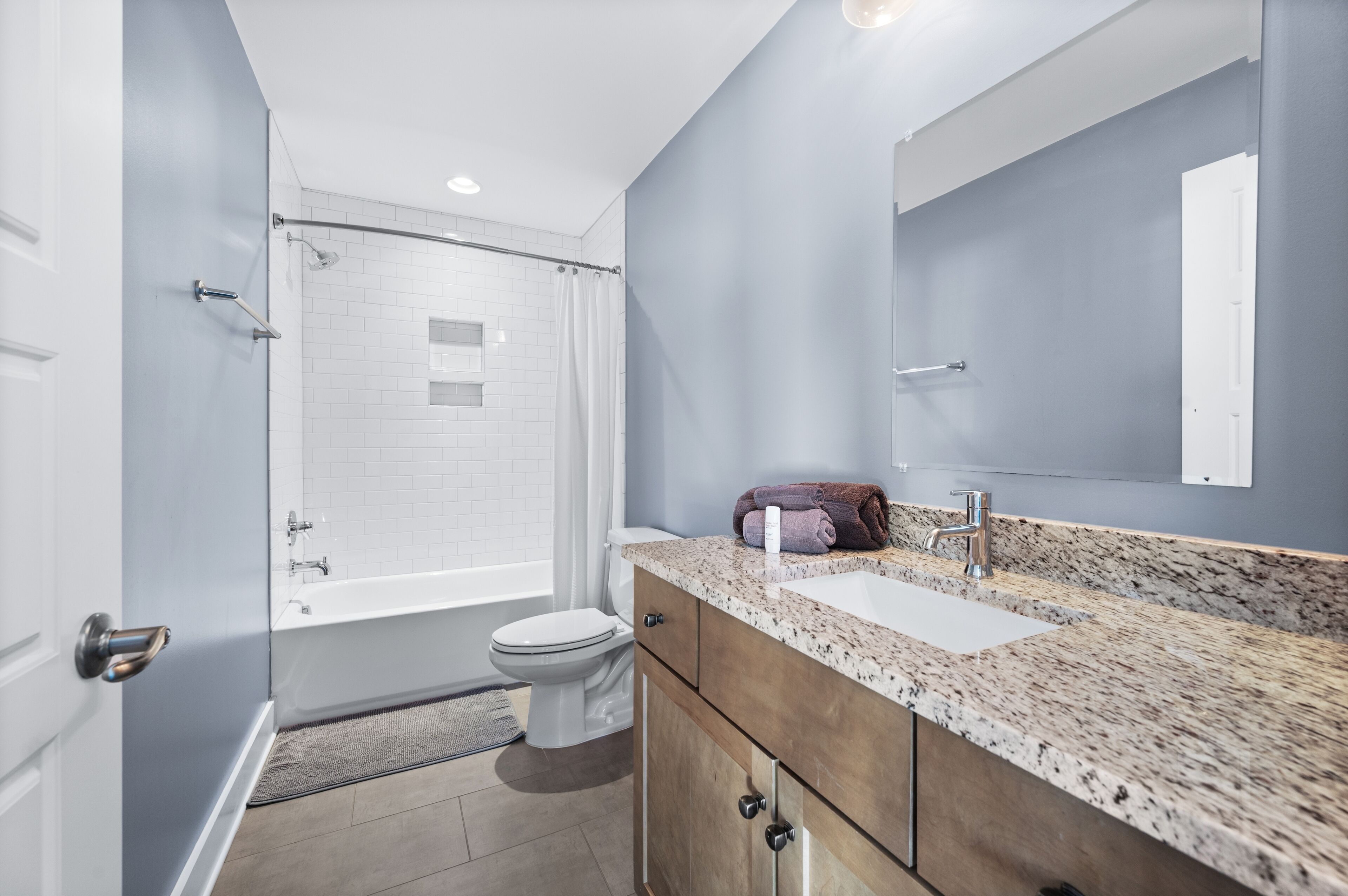 A modern bathroom with a shower, toilet, sink, and a large mirror.