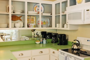 A kitchen with white cabinets, a green countertop, and various kitchen appliances.