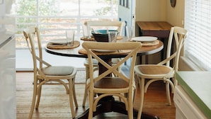 Un coin repas avec une table ronde, quatre chaises et un luminaire suspendu.
