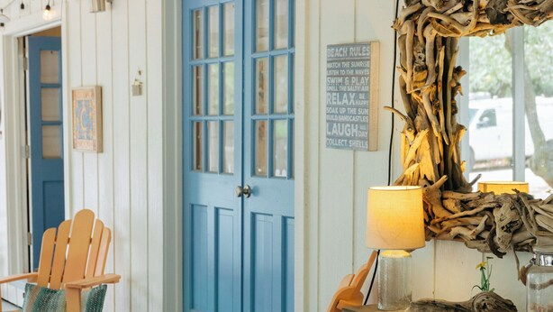 Une pièce chaleureuse avec une table en bois, des chaises, une porte bleue et un ventilateur de plafond.
