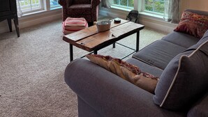A living room with a sofa, a chair, a small table, and large windows offering a view of greenery and a distant landscape. - Walk to Potomac River and downtown Harpers Ferry (Knoxville)