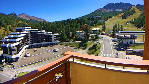 A view from a balcony overlooking a parking lot, buildings, and a mountainous landscape. - Charming 2-Room Cabin Apt, 40m², Sleeps 4, Near Vars Les Claux Slopes (Vars)