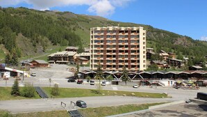 A multi-story hotel with a central courtyard, surrounded by smaller buildings and a mountainous backdrop. - Charming 2-Room Cabin Apt, 40m², Sleeps 4, Near Vars Les Claux Slopes (Vars)