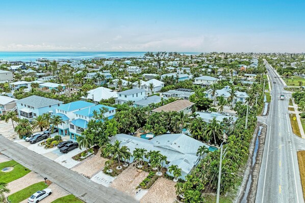 Un área residencial costera con casas, una carretera y una playa al fondo.