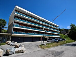 A multi-story hotel with balconies, a parking area, and a construction crane in the background.