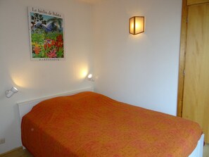 Un dormitorio con cama, una lámpara de pared y un cartel con un jardín.