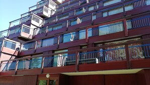 Um edifício com várias andares, varandas, porta de madeira e grade de metal.