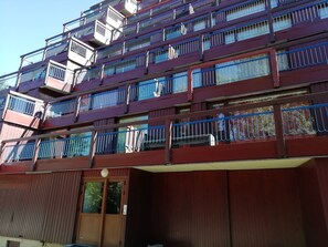 Un edificio de varios pisos con balcones, una puerta de madera y una barandilla de metal.