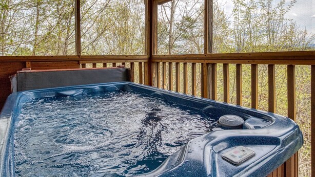 Un bain à remous sur une terrasse en bois, avec vue sur les arbres.