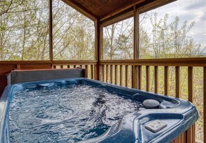 Un bain à remous sur une terrasse en bois, avec vue sur les arbres.