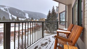 En balkong med trämöbler och utsikt över snötäckta berg.