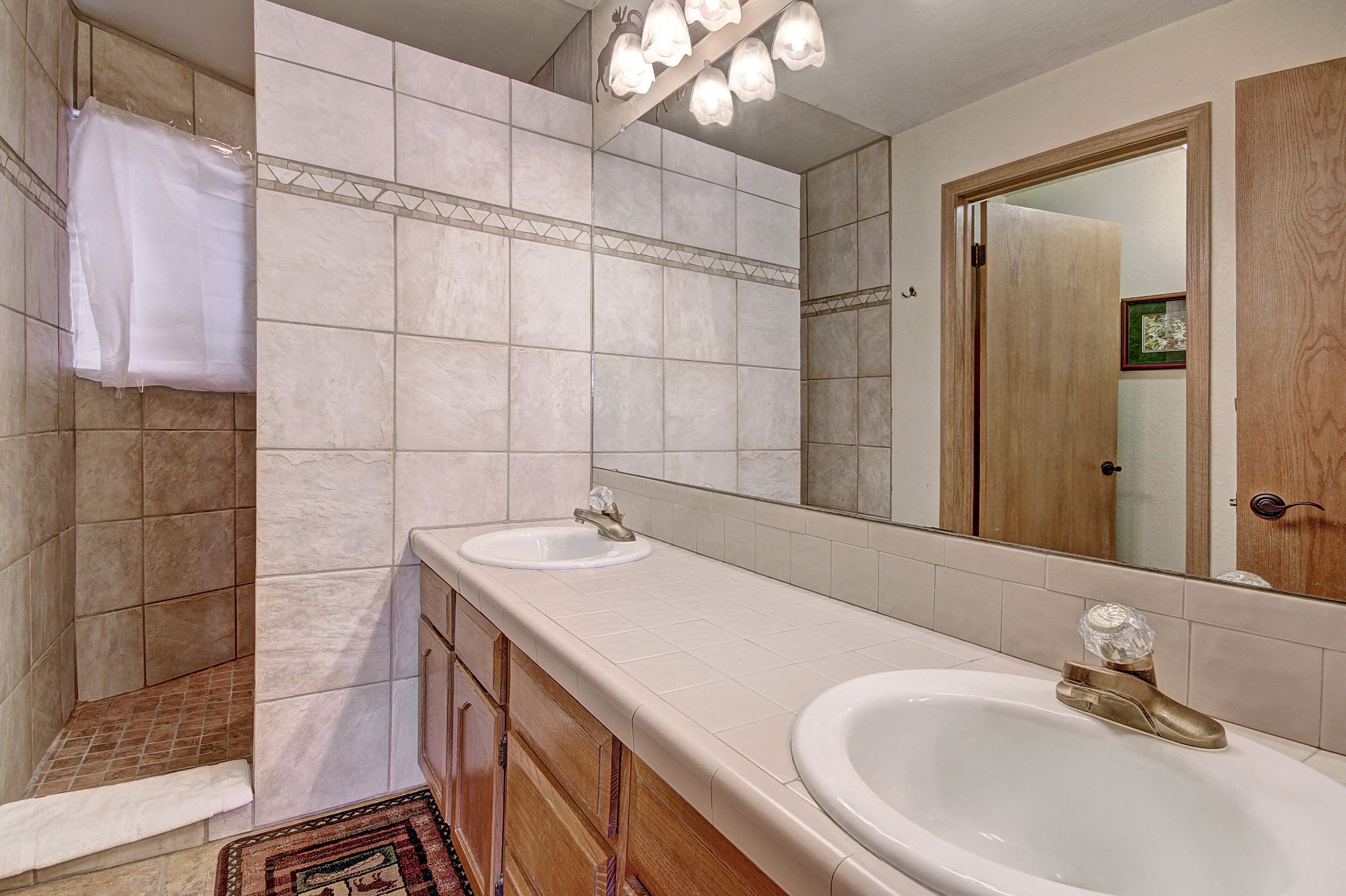 Un bagno con due lavandini, una doccia e uno specchio grande.