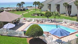 A pool area with a fenced deck, lounge chairs, and umbrellas. - Blue Surf 12A- 1bd townhome with community pool! (Miramar Beach)