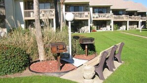 A hotel with a well-maintained lawn, outdoor seating area, and a mailbox. - Blue Surf 12A- 1bd townhome with community pool! (Miramar Beach)