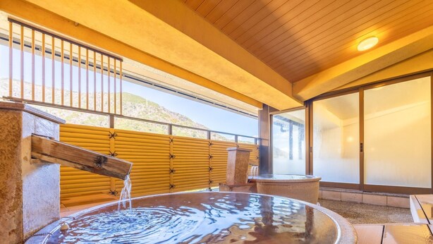 A hot spring bath area with a wooden deck, a stone basin, and a view of the surrounding landscape. - Hakoneji Kaiun (Hakone)