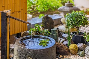 A traditional water pump with a wooden handle, surrounded by rocks and greenery. - Hakoneji Kaiun (Hakone)