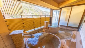 A hot spring bath area with wooden flooring, stone benches, and a view of a hillside. - Hakoneji Kaiun (Hakone)