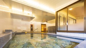 A swimming pool with a stone mosaic floor, a reception area with a bench, and a large glass door leading to another room. - Hakoneji Kaiun (Hakone)