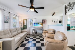 A living room with a checkered floor, a ceiling fan, a television, and a sign reading 'PARIS' on the wall. - Very quiet and private to rejuvenate your soul. Relax in the backyard and watch (Port Aransas)