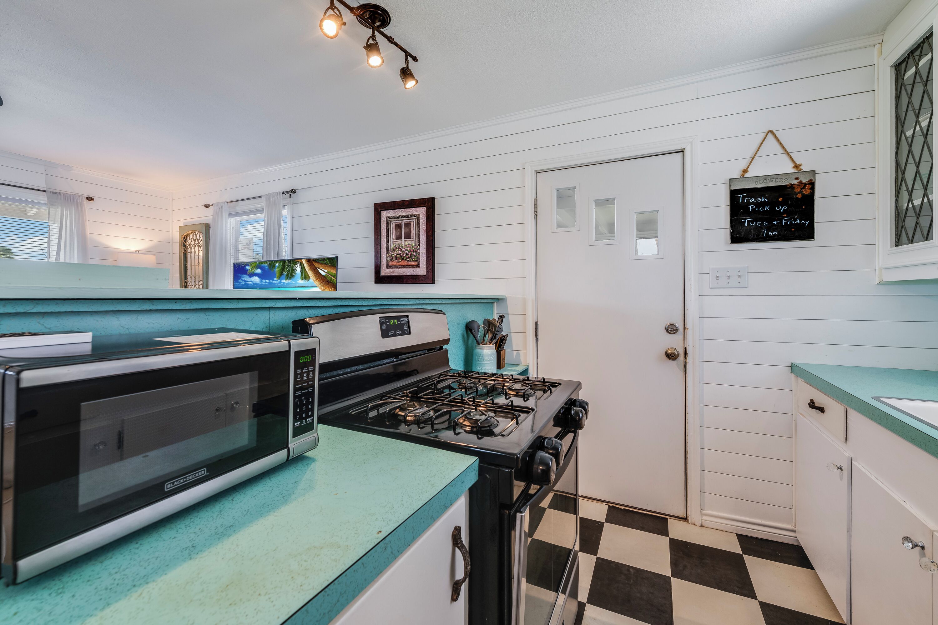 A kitchen with a microwave, stove, and teal countertop.
