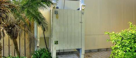 A wooden gate with a metal handle, a concrete step, and a metal door frame.