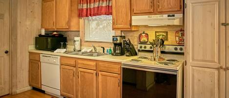 A kitchen with wooden cabinets, a stove, a microwave, and a dishwasher.