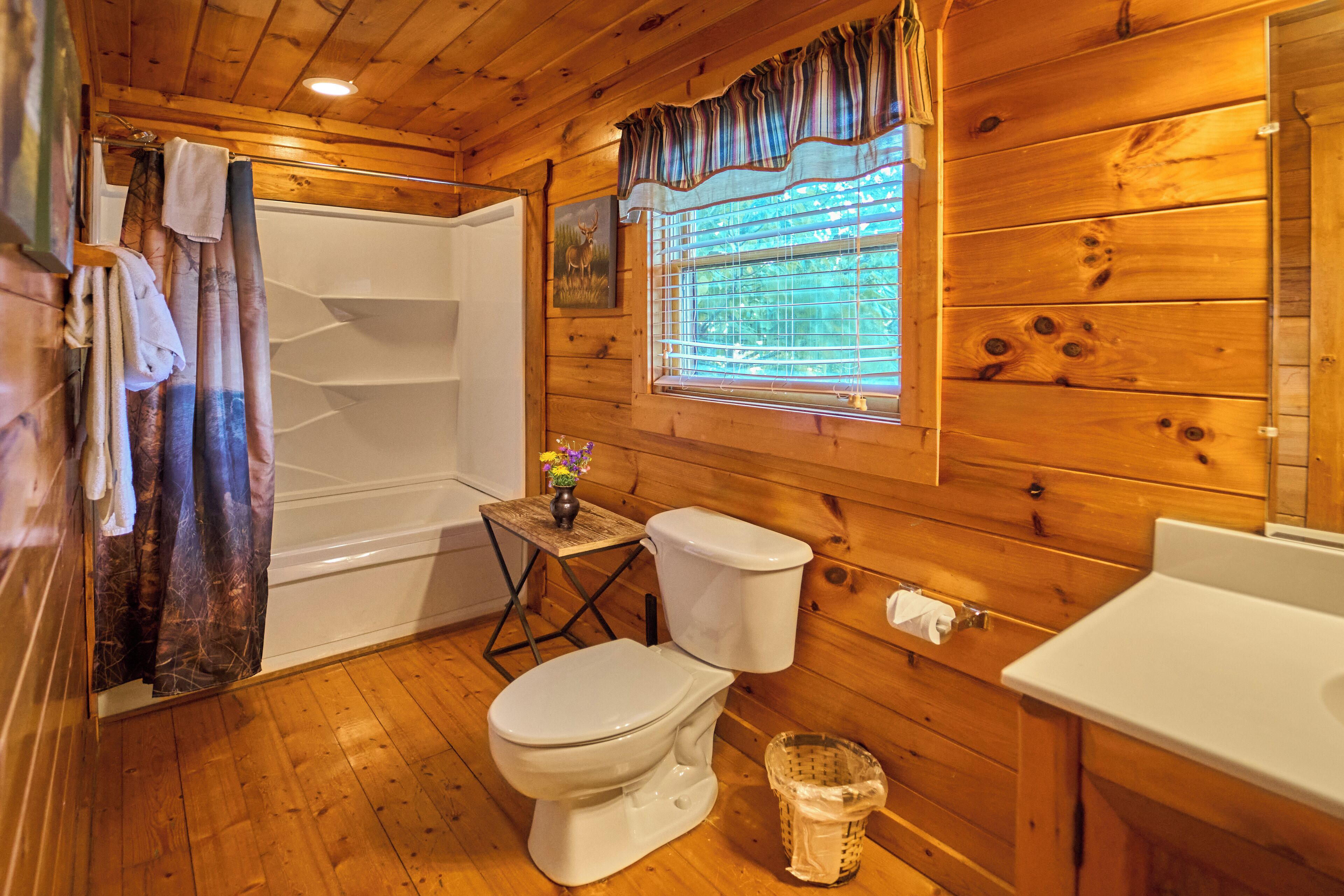 A wooden cabin bathroom with a shower, toilet, and sink.