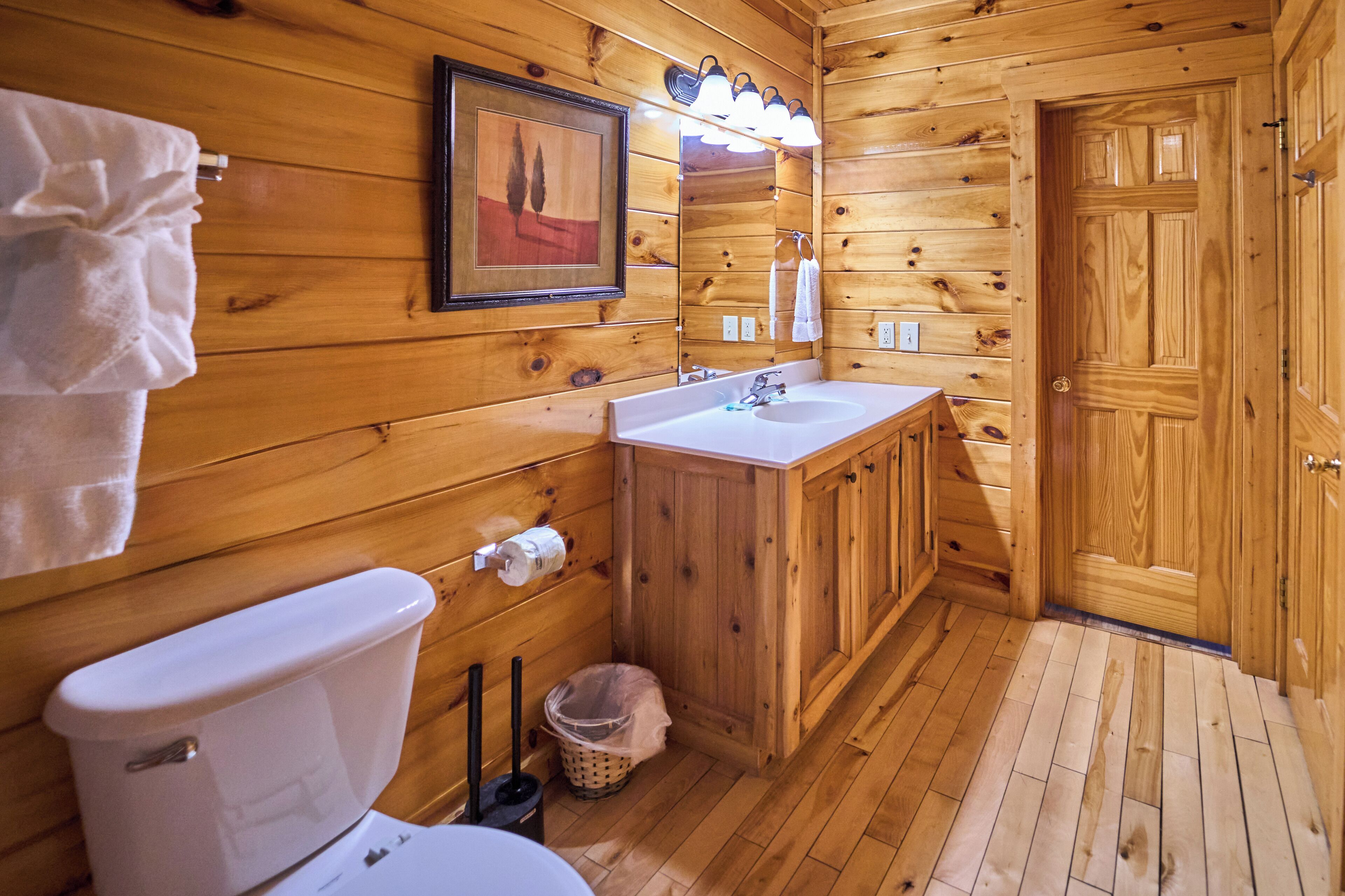 A wooden cabin bathroom with a toilet, sink, and mirror.