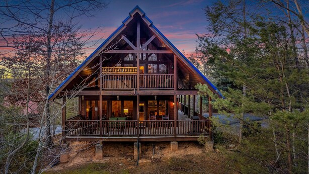 Eine zweistöckige Blockhütte mit Balkon, umgeben von Bäumen.