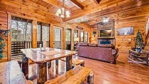 Ein Holzblockhaus-Interieur mit Esstisch, Bänken, einer Couch und einem Schaukelstuhl.
